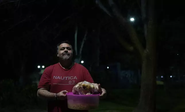 Weekend security guard Leonardo Constantino stops to pose for a portrait as he walks home with food for his family that he received from a soup kitchen in Buenos Aires, Argentina, Wednesday, Sept. 18, 2024. (AP Photo/Natacha Pisarenko)