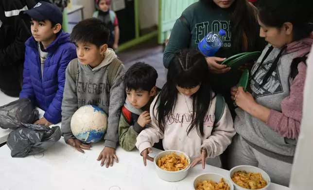 Children wait for a free, cooked meal at a soup kitchen on the outskirts of Buenos Aires, Argentina, Monday, Sept. 9, 2024. (AP Photo/Natacha Pisarenko)