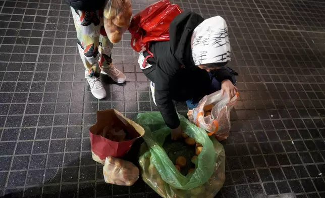 A girl and her mother collect baked goods outside a bakery that gives away what they don't sell by the end of the day, in Buenos Aires, Argentina, Monday, Sept. 9, 2024. (AP Photo/Natacha Pisarenko)