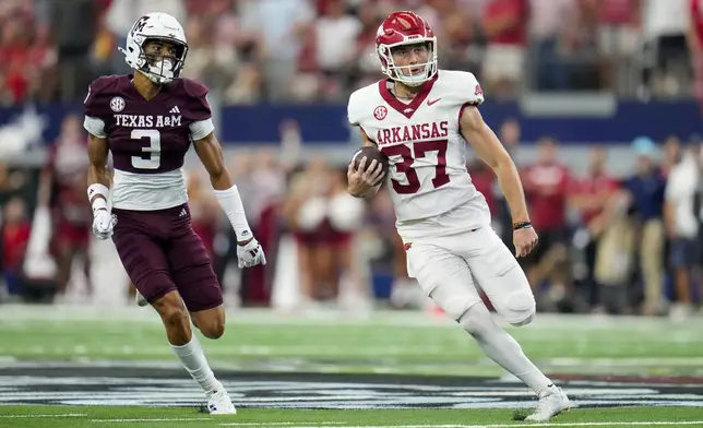 Arkansas punter Devin Bale, right, runs with the ball with Texas A&amp;M defensive back Marcus Ratcliffe in tow while running a fake punt play for a first down during the first half of an NCAA college football game, Saturday, Sept. 28, 2024, in Arlington, Texas. (AP Photo/Julio Cortez)