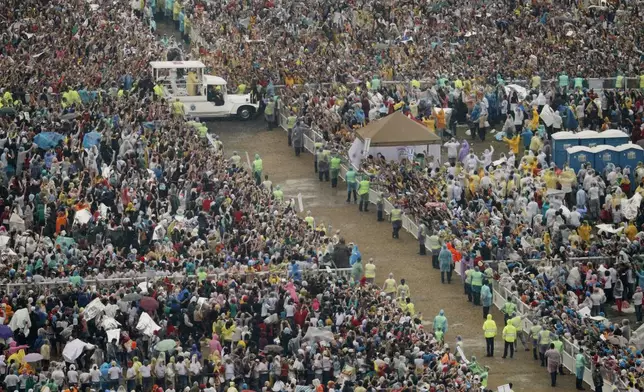 FILE - Pope Francis, in the vehicle, waves to the faithful as he arrives at Rizal Park to celebrate his final Mass in Manila, Philippines, on Jan. 18, 2015. (AP Photo/Wally Santana, File)