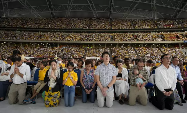 The faithful follow Pope Francis presiding over a mass 'In Memory of the Most Holy Name of Mary' celebrated by the Archbishop of Singapore, Cardinal William Goh Seng Chye at the Singapore SportsHub National Stadium, Thursday, Sept. 12, 2024. In the farthest trip of his pontificate and one of the longest papal trips ever in terms of days on the road and distance traveled, Pope Francis, age 87, hobbled by bad knees and bent over with sciatica, appeared to be having the time of his life. (AP Photo/Gregorio Borgia)