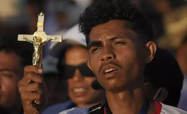 A catholic faithful holds a crucifix during the holy mass presided over by Pope Francis at Tasitolu Park in Dili, East Timor, Tuesday, Sept. 10, 2024. With half of East Timor's population gathered at a seaside park, Francis couldn't help but oblige them with a final good night and languid loops in his popemobile, long after the sun had set and cellphone screens lighted the field. (AP Photo/Dita Alangkara, Pool)