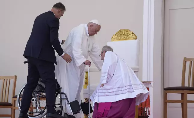 Pope Francis is helped by his aide Archbishop Diego Ravelli, right, as he arrives on the altar to preside over a votive mass of the Blessed Virgin Mary Queen in Tasitolu, some 8 kilometers west of Dili, East Timor, Tuesday, Sept. 10, 2024. (AP Photo/Gregorio Borgia)