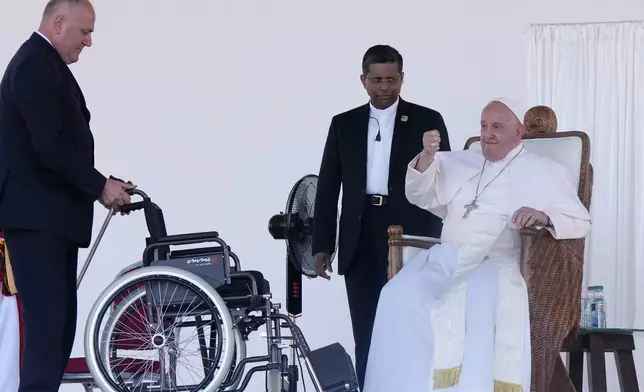 An aide brings a wheelchair for Pope Francis after he gave an address in the Sir John Guise Stadium in Port Moresby, Papua New Guinea, Monday, Sept. 9, 2024. (AP Photo/Mark Baker)