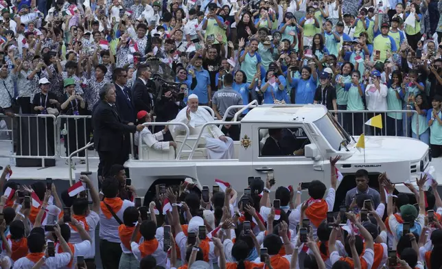 People react as Pope Francis arrives at Madya Stadium in Jakarta, Indonesia, Thursday, Sept. 5, 2024. (AP Photo/Tatan Syuflana)