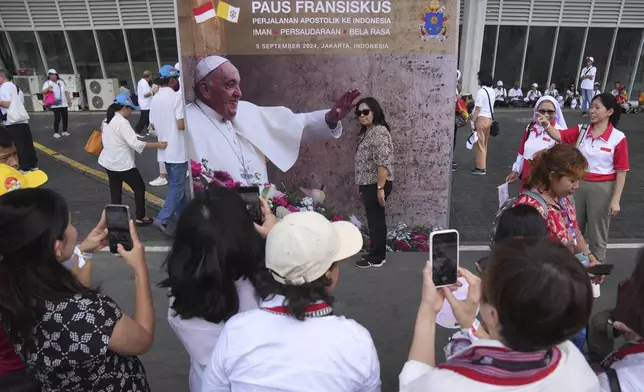 A woman has her photo taken with a Pope Francis backdrop ahead of the holy Mass led by the pope at Gelora Bung Karno Stadium in Jakarta, Indonesia, Thursday, Sept. 5, 2024. (AP Photo/Dita Alangkara)