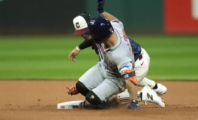 Houston Astros' Jose Altuve, front, slides safely into second base as Cleveland Guardians second baseman Andres Gimenez, back, applies a tag in the first inning of a baseball game in Cleveland, Friday, Sept. 27, 2024. (AP Photo/Sue Ogrocki)