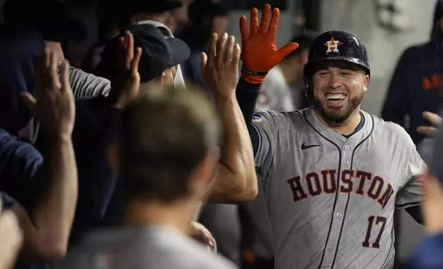 Houston Astros' Victor Caratini (17) is congratulated in the dugout after hitting a home run in the fifth inning of a baseball game against the Cleveland Guardians in Cleveland, Friday, Sept. 27, 2024. (AP Photo/Sue Ogrocki)