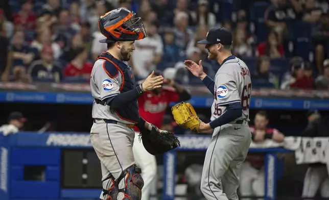 Houston Astros' Victor Caratini, left congratulates Shawn Dubin, right at the end of a baseball game against the Cleveland Guardians in Cleveland, Saturday, Sept. 28, 2024. (AP Photo/Phil Long)