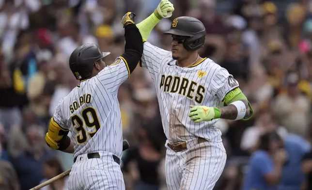 San Diego Padres' Manny Machado, right, celebrates with teammate Donovan Solano after hitting a home run during the sixth inning of a baseball game against the Houston Astros Wednesday, Sept. 18, 2024, in San Diego. (AP Photo/Gregory Bull)