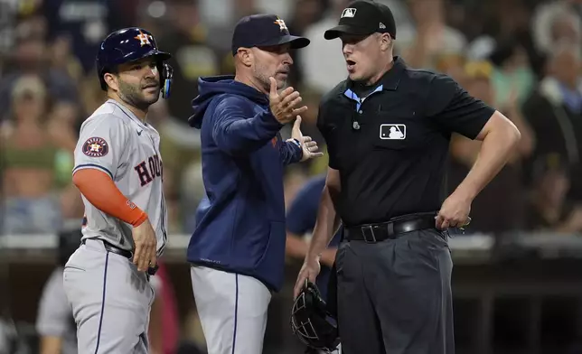 Houston Astros manager Joe Espada, center, argues with home plate umpire Brennan Miller, right, as second baseman Jose Altuve looks on during the ninth inning of a baseball game against the San Diego Padres Tuesday, Sept. 17, 2024, in San Diego. Espada and Altuve were ejected after arguing a groundout by Altuve was fouled off his foot. (AP Photo/Gregory Bull)