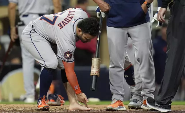 Houston Astros' Jose Altuve points at his foot after taking his sock and shoe off during the ninth inning of a baseball game against the San Diego Padres Tuesday, Sept. 17, 2024, in San Diego. Altuve was ejected along with Astros manager Joe Espada after arguing a groundout by Altuve was fouled off his foot. (AP Photo/Gregory Bull)