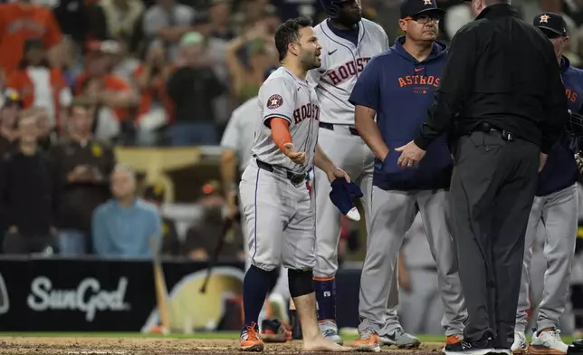 Houston Astros' Jose Altuve reacts towards home plate umpire Brennan Miller, right, after taking his sock and shoe off during the ninth inning of a baseball game against the San Diego Padres Tuesday, Sept. 17, 2024, in San Diego. Altuve was ejected along with Astros manager Joe Espada after arguing a groundout by Altuve was fouled off his foot. (AP Photo/Gregory Bull)