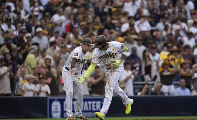 San Diego Padres' Manny Machado, right, celebrates with third base coach Tim Leiper after hitting a home run during the sixth inning of a baseball game against the Houston Astros Wednesday, Sept. 18, 2024, in San Diego. (AP Photo/Gregory Bull)