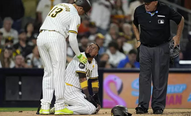 San Diego Padres' Luis Arraez, center, talks with Manny Machado, left after being tagged out trying to score from second base on a single by Jurickson Profar during the fifth inning of a baseball game against the Houston Astros as home plate umpire Brian O'Nora looks on Monday, Sept. 16, 2024, in San Diego. (AP Photo/Gregory Bull)