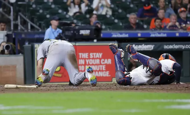 Oakland Athletics' Zack Gelof, left, is safe at home plate as he scores on the sacrifice bunt by Max Schuemann as Houston Astros catcher Victor Caratini, right, reaches for the ball during the 12th inning of a baseball game Tuesday, Sept. 10, 2024, in Houston. (AP Photo/Michael Wyke)