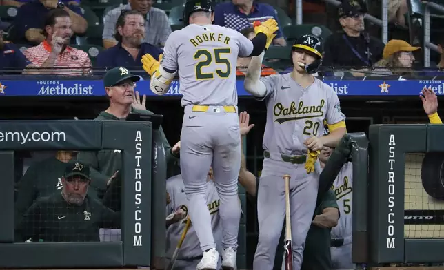 Oakland Athletics designated hitter Brent Rooker (25) high-fives Zack Gelof (20) at the dugout after after hitting a solo home run against the Houston Astros during the eighth inning of a baseball game Thursday, Sept. 12, 2024, in Houston. (AP Photo/Michael Wyke)