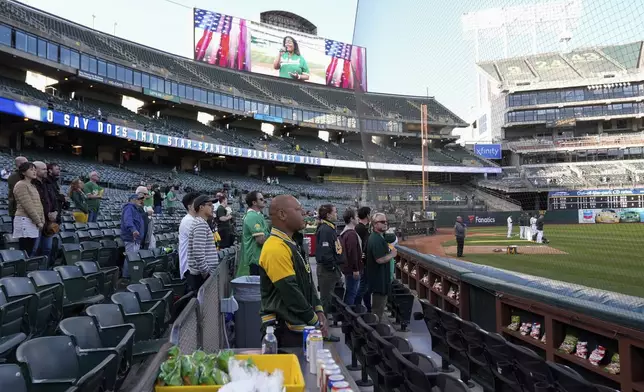 Derrick Smith, center, listens to the national anthem before the start of a baseball game between the Colorado Rockies and the Oakland Athletics, Wednesday, May 22, 2024, in Oakland, Calif. (AP Photo/Godofredo A. Vásquez)