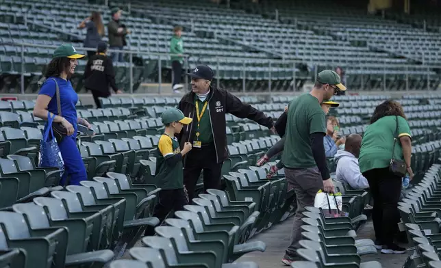 Leland Anderson, center, guides people to their seats before a baseball game between the Colorado Rockies and the Oakland Athletics, Wednesday, May 22, 2024, in Oakland, Calif. (AP Photo/Godofredo A. Vásquez)