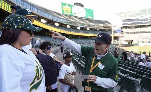 Leland Anderson, right, speaks with fans attending a baseball game between the Colorado Rockies and the Oakland Athletics, Wednesday, May 22, 2024, in Oakland, Calif. (AP Photo/Godofredo A. Vásquez)