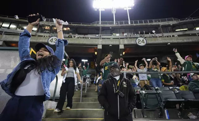 Charles Riley, center, stands guard in section 122 as fans cheer during a baseball game between the New York Yankees and the Oakland Athletics, Saturday, Sept. 21, 2024, in Oakland, Calif. (AP Photo/Godofredo A. Vásquez)