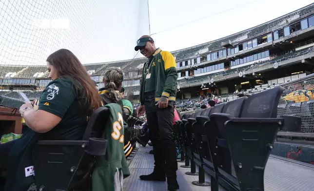 Derrick Smith, center, greets fans sitting in his section during a baseball game between the Colorado Rockies and the Oakland Athletics, Wednesday, May 22, 2024, in Oakland, Calif. (AP Photo/Godofredo A. Vásquez)