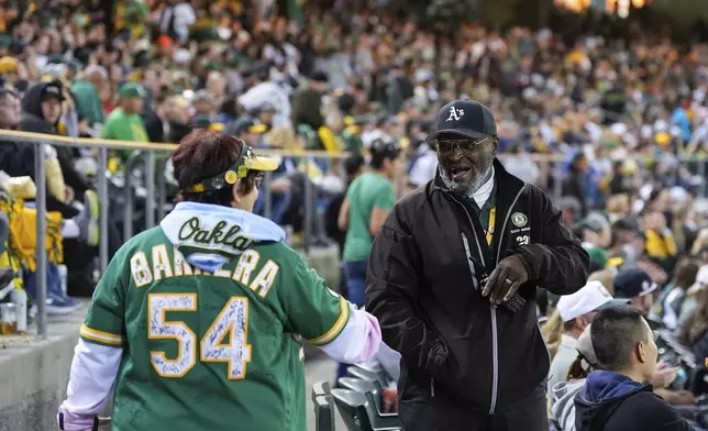 Charles Riley, right, greets a fan while working security in section 122 during a baseball game between the New York Yankees and the Oakland Athletics, Saturday, Sept. 21, 2024, in Oakland, Calif. (AP Photo/Godofredo A. Vásquez)