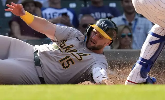 Oakland Athletics' Seth Brown, left, scores past Chicago Cubs catcher Miguel Amaya after Oakland Athletics' Zack Gelof hit a one-run double during the eighth inning of a baseball game in Chicago, Wednesday, Sept. 18, 2024. (AP Photo/Nam Y. Huh)