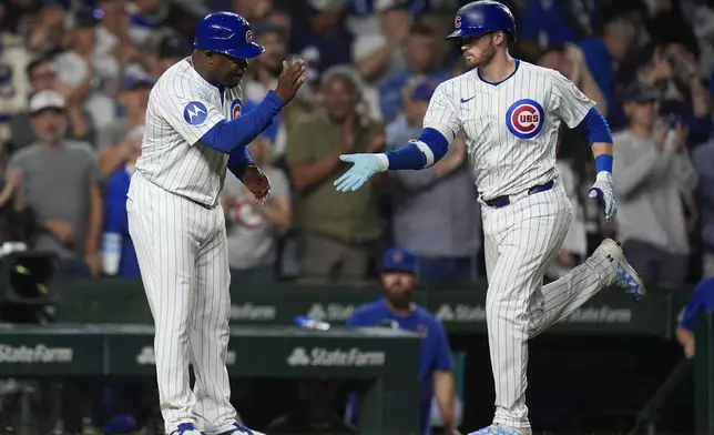 Chicago Cubs' Ian Happ, right, slaps hands with third base coach Willie Harris as he runs the bases on a home run during the third inning of a baseball game against the Oakland Athletics, Tuesday, Sept. 17, 2024, in Chicago. (AP Photo/Erin Hooley)