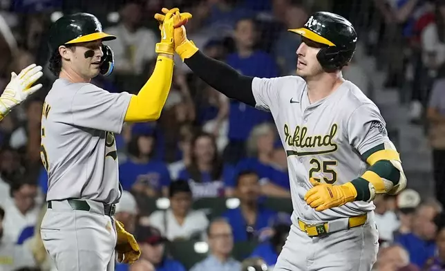 Oakland Athletics' Jacob Wilson, left, greets Brent Rooker at home after they both scored on Rooker's two-run home run off Chicago Cubs starting pitcher Shota Imanaga during the third inning of a baseball game Monday, Sept. 16, 2024, in Chicago. (AP Photo/Charles Rex Arbogast)