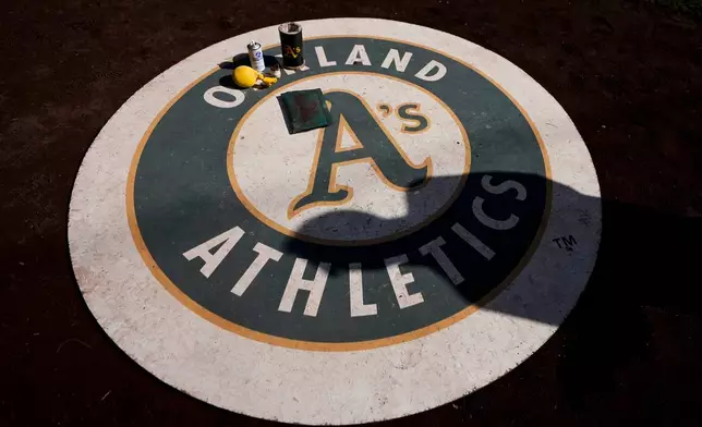 A person casts a shadow on the Oakland Athletics on-deck circle before a baseball game against the Seattle Mariners, Sunday, Sept. 29, 2024, in Seattle. (AP Photo/Lindsey Wasson)