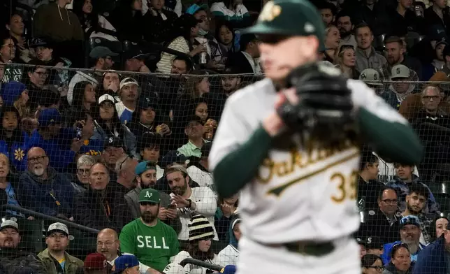 A fan wears a "sell" shirt as Oakland Athletics starting pitcher JP Sears warms up on the mound before facing the Seattle Mariners in the fourth inning of a baseball game, Friday, Sept. 27, 2024, in Seattle. (AP Photo/Lindsey Wasson)