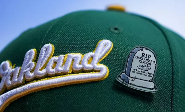 A fan wears an Oakland Athletics hat with a pin referencing the end of the team's time in Oakland before a baseball game against the Seattle Mariners, Sunday, Sept. 29, 2024, in Seattle. (AP Photo/Lindsey Wasson)