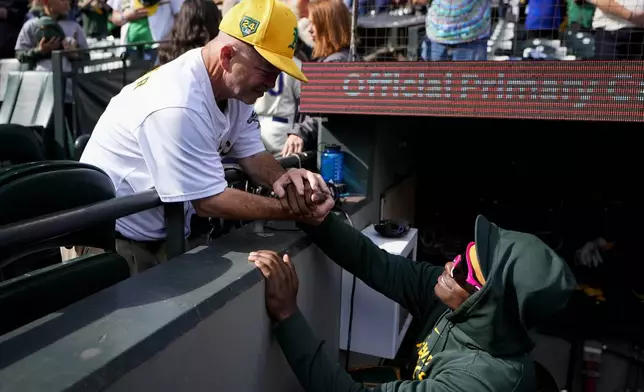 Fan Michael Marler, also known as "Road Trip Mike," greets Oakland Athletics right fielder Lawrence Butler before a baseball game against the Seattle Mariners, Sunday, Sept. 29, 2024, in Seattle. (AP Photo/Lindsey Wasson)