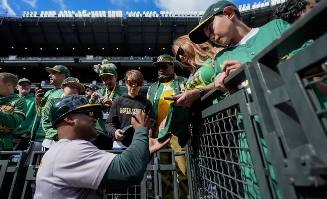 Oakland Athletics third base coach Eric Martins signs autographs for fans before a baseball game against the Seattle Mariners, Sunday, Sept. 29, 2024, in Seattle. (AP Photo/Lindsey Wasson)