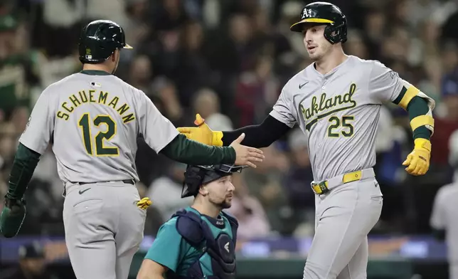 Oakland Athletics' Brent Rooker (25) is greeted by Max Schuemann (12) after both scored on Rooker's two-run home run on a pitch from Seattle Mariners starting pitcher Emerson Hancock during the fifth inning in a baseball game, Saturday, Sept. 28, 2024, in Seattle. (AP Photo/John Froschauer)