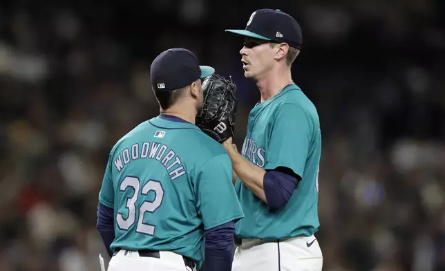 Seattle Mariners starting pitcher Emerson Hancock, right, talks on the mound with pitching coach Pete Woodworth (32) after loading the bases with a walk during the third inning against the Oakland Athletics in a baseball game, Saturday, Sept. 28, 2024, in Seattle. (AP Photo/John Froschauer)