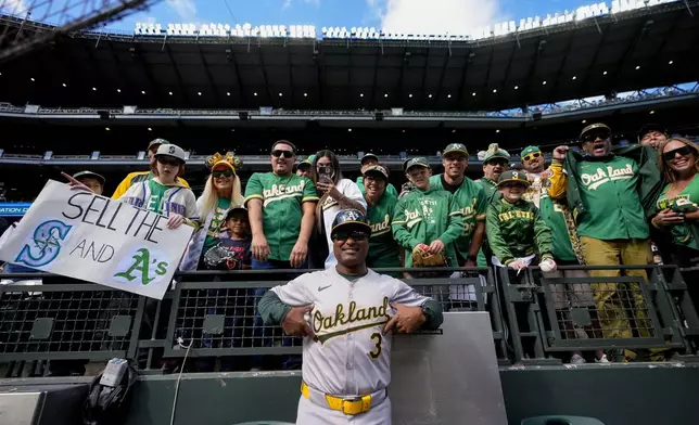 Oakland Athletics third base coach Eric Martins (3) poses with fans before a baseball game against the Seattle Mariners, Sunday, Sept. 29, 2024, in Seattle. (AP Photo/Lindsey Wasson)