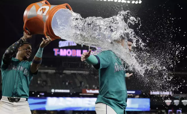 Seattle Mariners'm Julio Rodríguez dumps water on Justin Turner after he hit the game winning run against the Oakland Athletics to win 7-6 in a baseball game, Saturday, Sept. 28, 2024, in Seattle. (AP Photo/John Froschauer)