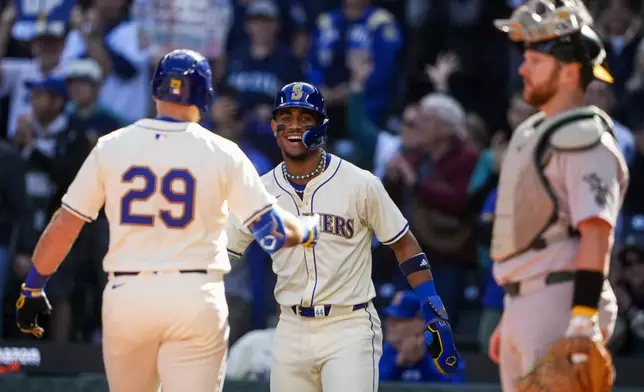 Seattle Mariners' Julio Rodríguez, facing, greets Cal Raleigh (29) after scoring on Raleigh's two-run home run against the Oakland Athletics during the fifth inning of a baseball game, Sunday, Sept. 29, 2024, in Seattle. (AP Photo/Lindsey Wasson)