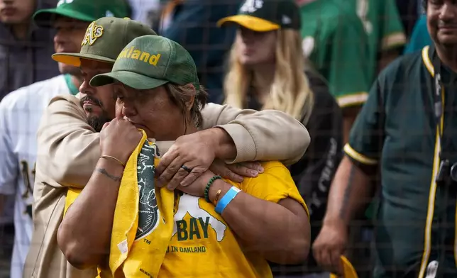 Oakland Athletics fans hug each other and look towards the team's dugout following the Athletics' 6-4 loss to the Seattle Mariners in a baseball game, Sunday, Sept. 29, 2024, in Seattle. (AP Photo/Lindsey Wasson)