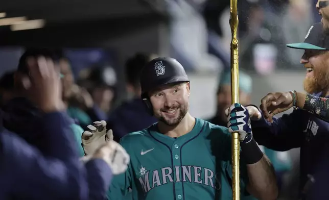 Seattle Mariners' Cal Raleigh is congratulated in the dugout after hitting a solo home run off Oakland Athletics starting pitcher Joey Estes during the fourth inning in a baseball game, Saturday, Sept. 28, 2024, in Seattle. (AP Photo/John Froschauer)