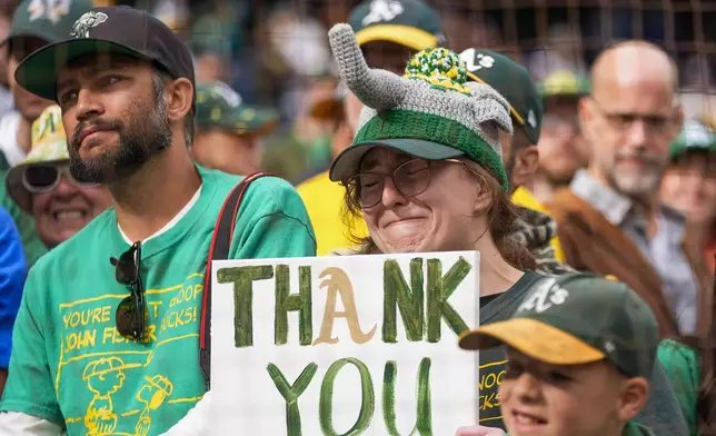 An Oakland Athletics fan cries while holding up a "thank you" sign towards the team's dugout following the Athletics' 6-4 loss to the Seattle Mariners in a baseball game, Sunday, Sept. 29, 2024, in Seattle. (AP Photo/Lindsey Wasson)