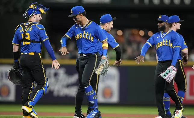 Seattle Mariners catcher Mitch Garver, left, greets center fielder Julio Rodríguez, second from left, as they celebrate a 2-0 win over the Oakland Athletics in a baseball game, Friday, Sept. 27, 2024, in Seattle. (AP Photo/Lindsey Wasson)