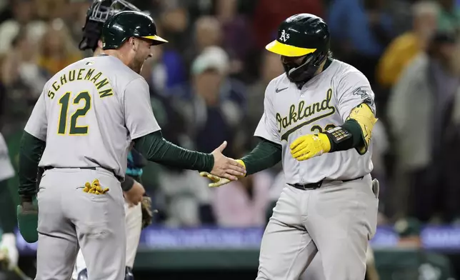 Oakland Athletics' Shea Langeliers, right, is greeted by Max Schuemann at home after hitting a three-run home run on a pitch from Seattle Mariners pitcher Collin Snider during the ninth inning in a baseball game, Saturday, Sept. 28, 2024, in Seattle. (AP Photo/John Froschauer)