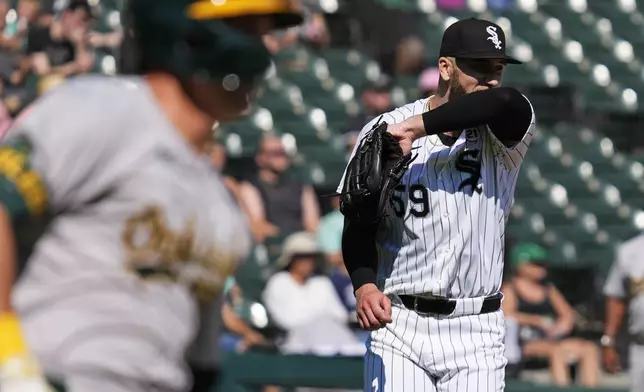 Chicago White Sox starting pitcher Sean Burke, right, wipes his face as Oakland Athletics' JJ Bleday, left, runs after hitting a double during the fifth inning of a baseball game in Chicago, Sunday, Sept. 15, 2024. (AP Photo/Nam Y. Huh)