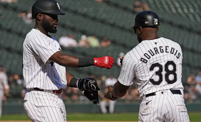 Chicago White Sox's Bryan Ramos, left, celebrates with first base coach Jason Bourgeois, right, after he walked to first during the eighth inning of a baseball game against the Oakland Athletics in Chicago, Sunday, Sept. 15, 2024. (AP Photo/Nam Y. Huh)