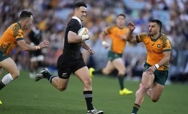 New Zealand's Will Jordan, center, races past Australia's Nic White, left, and Tom Wright to score a try during their rugby union test match in Sydney, Saturday, Sept. 21, 2024. (AP Photo/Rick Rycroft)