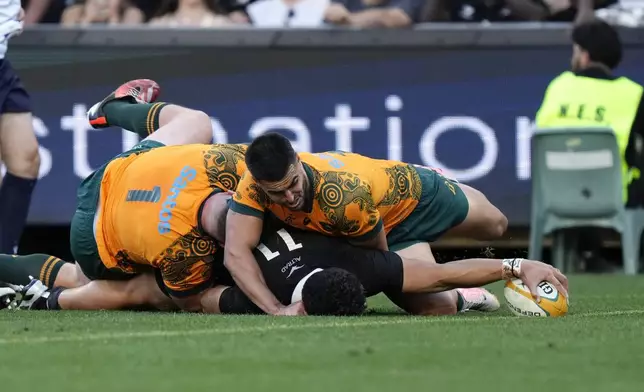 New Zealand's Caleb Clarke, bottom, scores a try as Australia's Angus Bell, left, and Tom Wright are unable to stop him during their rugby union test match in Sydney, Saturday, Sept. 21, 2024. (AP Photo/Rick Rycroft)